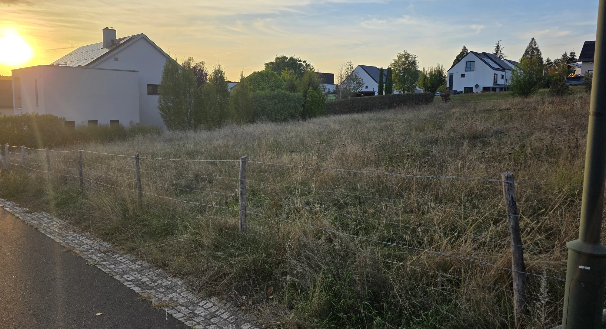 Unbebaute Fläche zwischen Wohnhäusern im Abendlicht